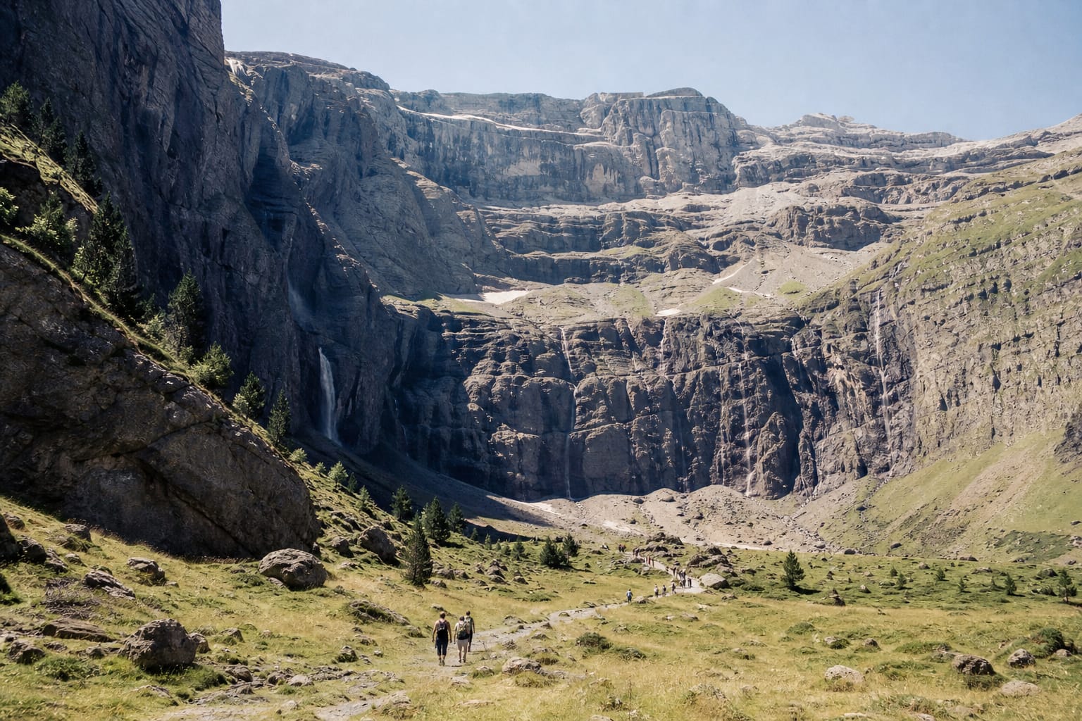 Randonneurs sur le sentier du cirque de Gavarnie, au pied de hautes parois calcaires striées de cascades